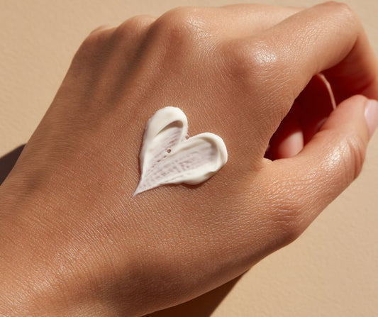 A person's hand with sunblock in the shape of a heart on it.