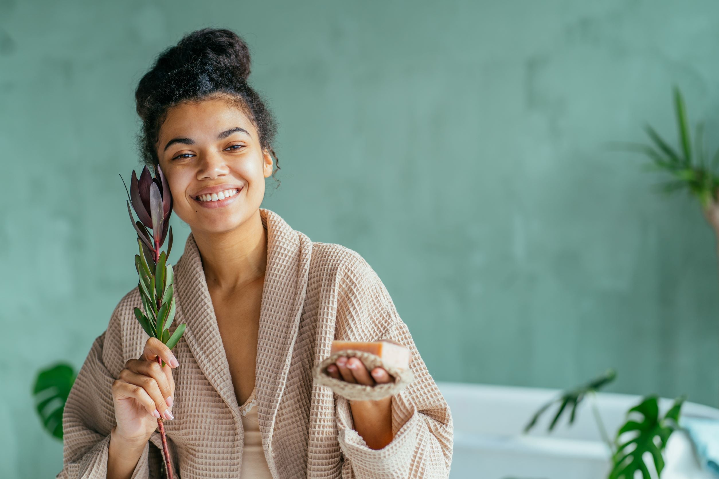 Beautiful smiling woman holding bar of natural soap. Enjoying a stress free spa day at home.